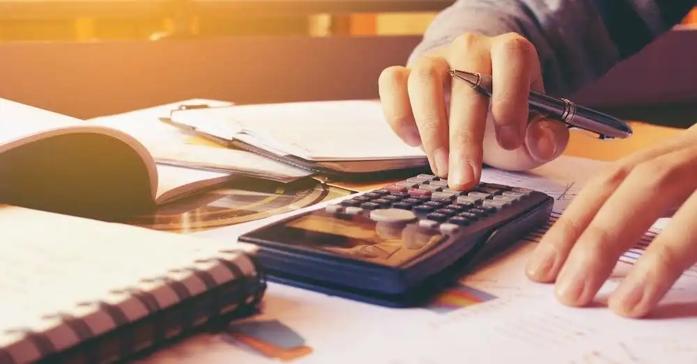 Henkilö tekemässä lainalaskelmia taskulaskimen avulla