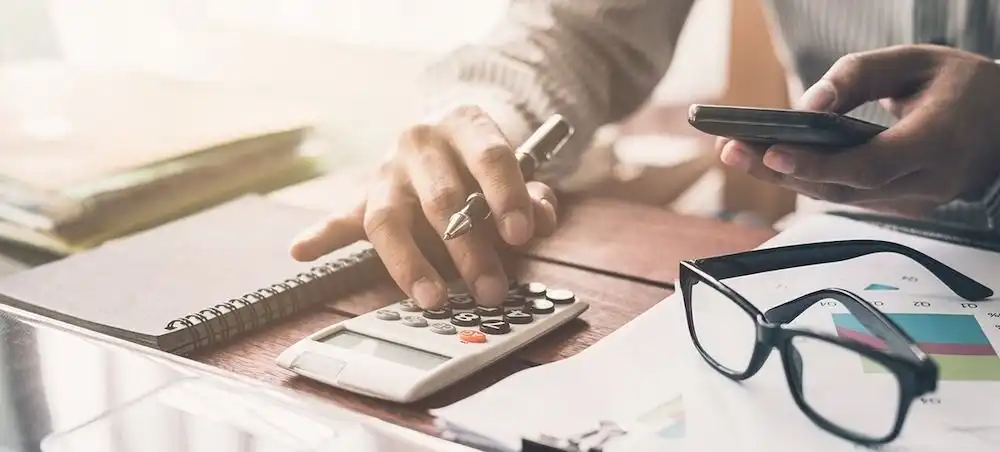 Henkilö laskemassa lainan kokonaiskustannuksia pöydän ääressä