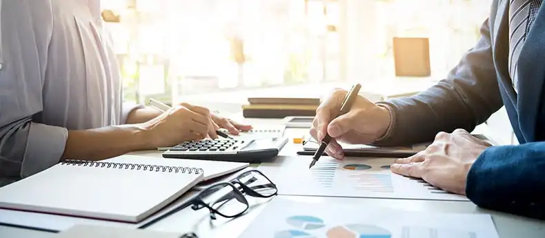 Kaksi henkilöä tutkimassa lainalaskelmia pöydän ääressä