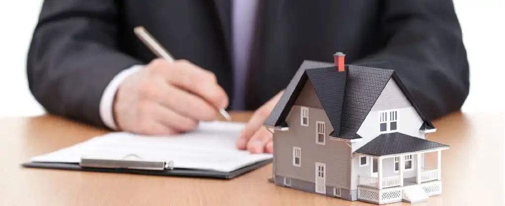 Pöydällä talon pienoismalli ja lainaehdot sisältävä paperi